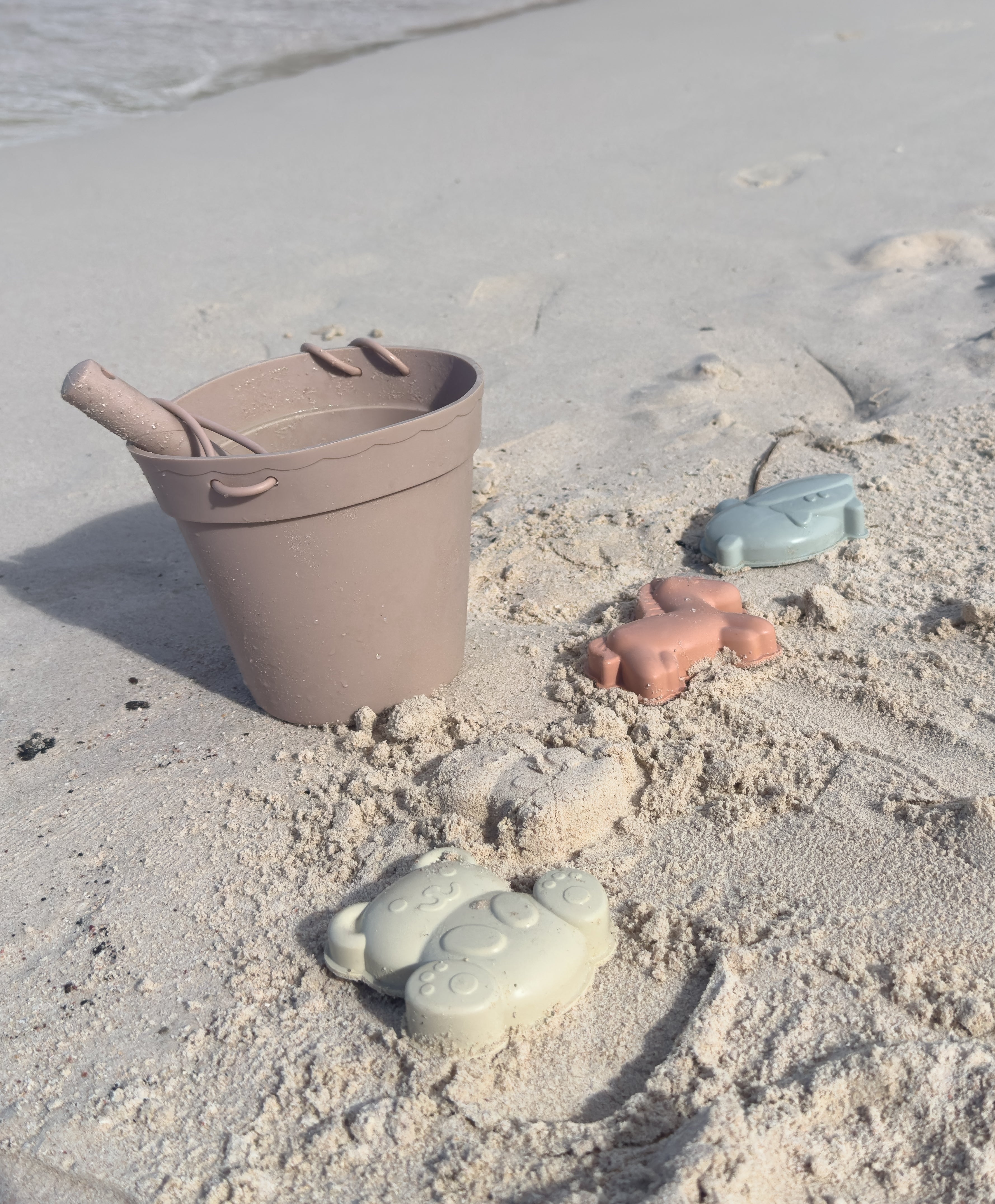 strandemmer in het zand met zandvormpjes van silconen.
